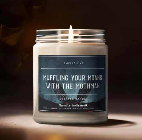 Candle whose label reads 'muffling your moans with the mothman'